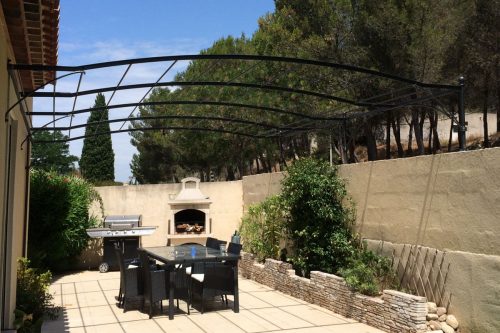Pergola forme chapeau de gendarme entre mur maison et muret